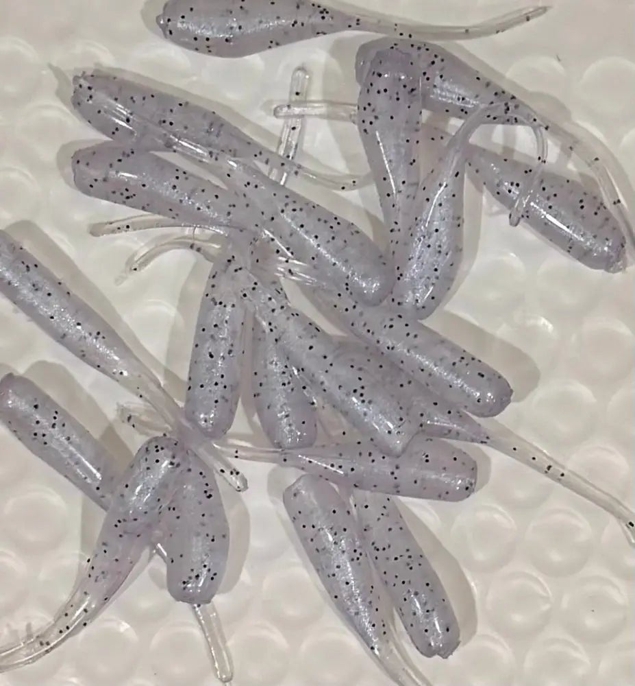 Soft plastic Crappie jig 2 inches long solid translucent clear with a blue accent and black glitter with a flat beaver tail