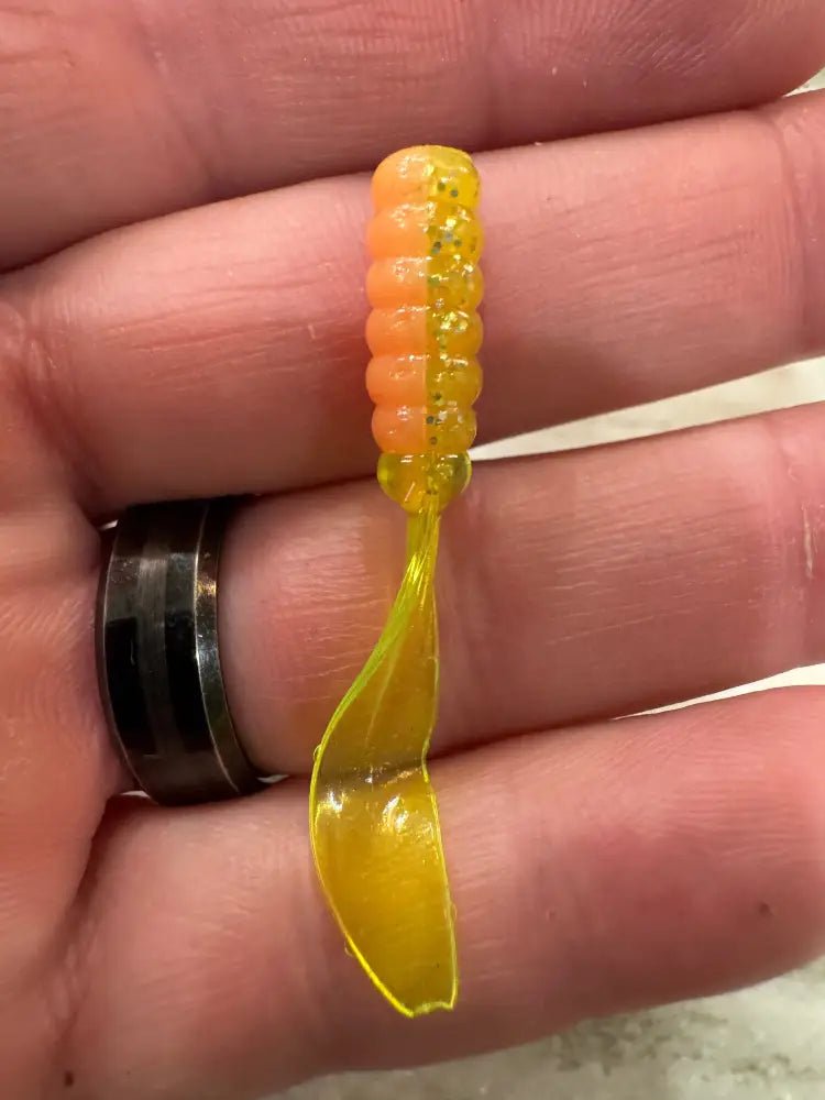 A Hand holding a Crappie jig with a two color pink and silver glitter chartreuse head and chartreuse flat beaver tail