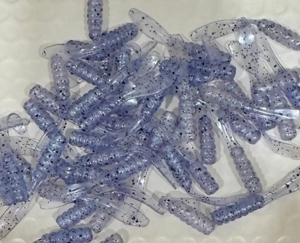 Multiple Soft plastic Crappie jigs 2 inches long translucent with a blue hue and black glitter with a flat beaver tail