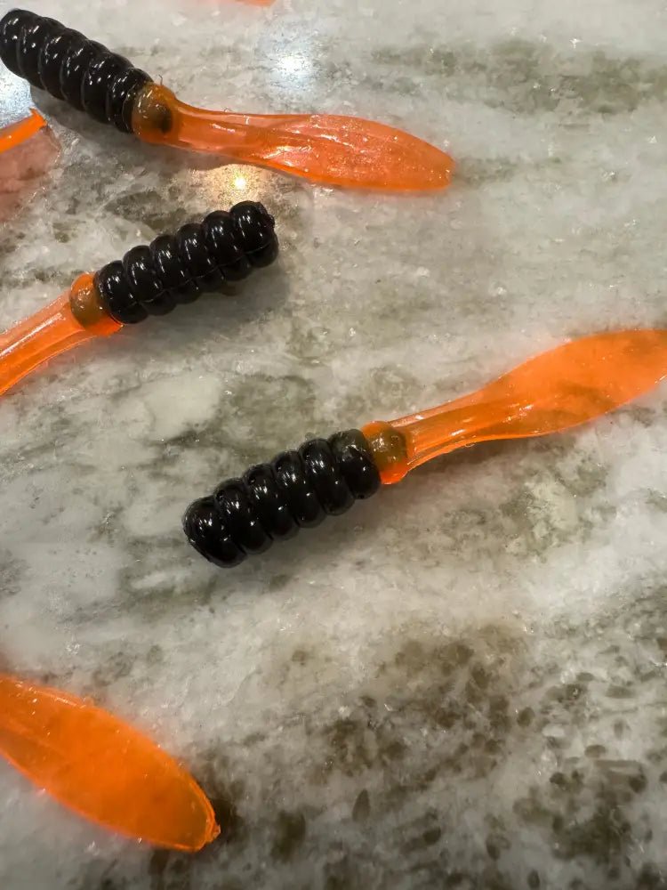 Soft plastic Crappie jig 2 inches long with a black head and shiny orange flat beaver tail