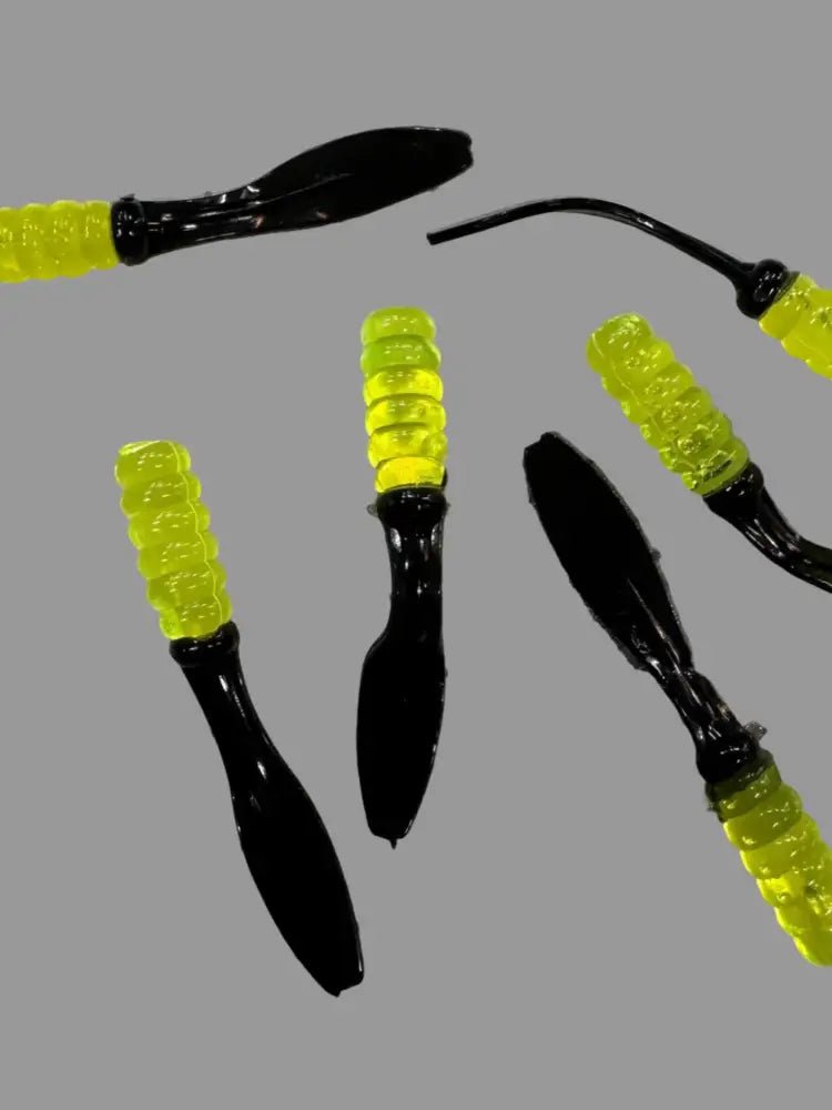 Soft plastic Crappie jigs 2 inches long with a translucent chartreuse head and a black flat beaver tail.