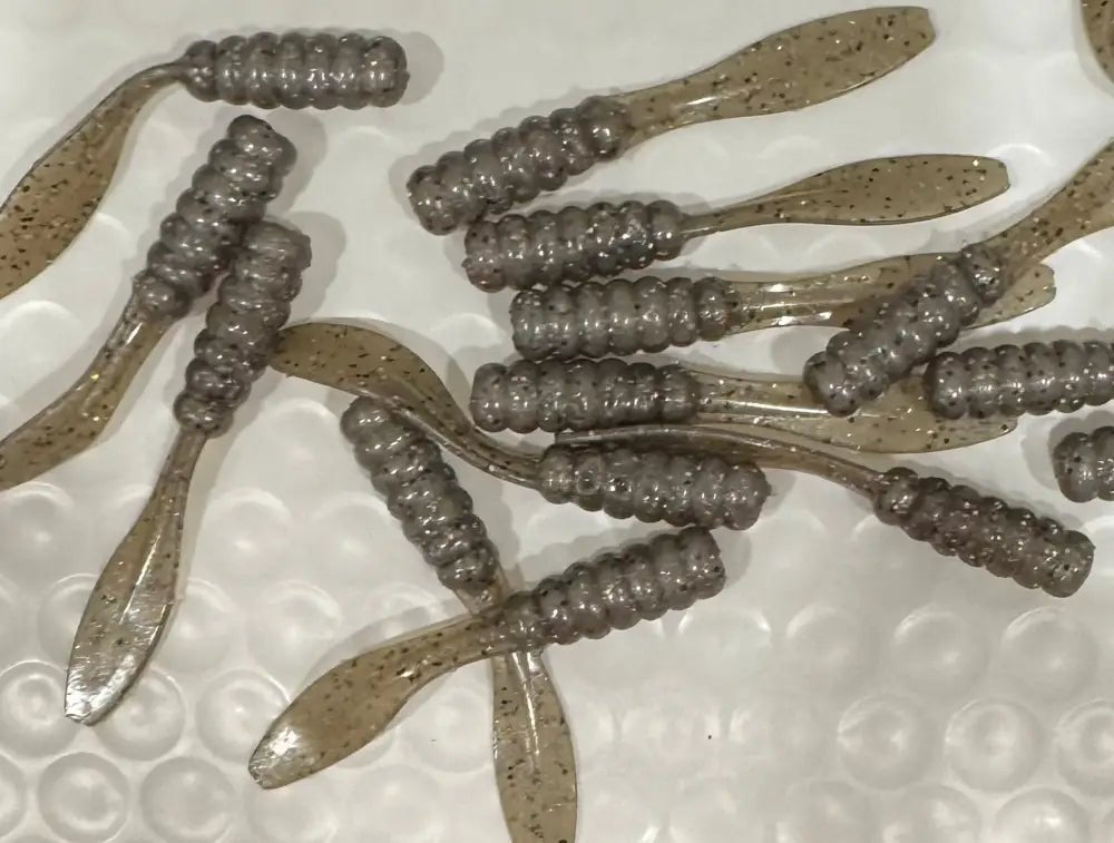 Soft plastic Crappie jig 2 inches solid color grayish in color with black silver and red glitter and a flat beaver tail