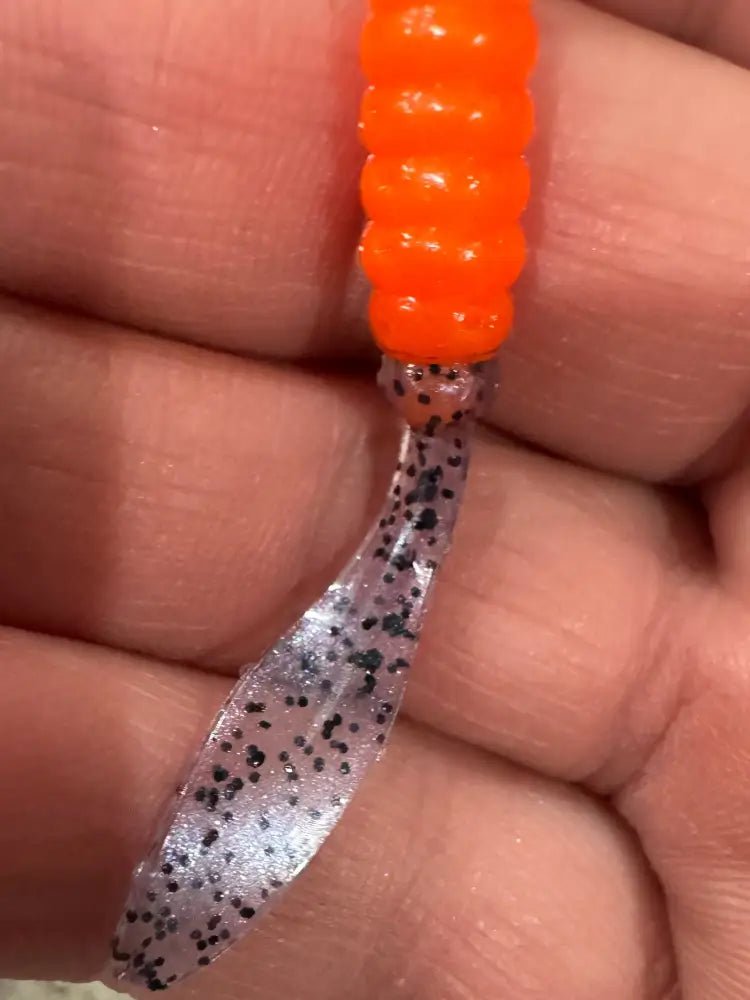 Soft plastic Crappie jig 2 inches long with a orange head and translucent blue flat beaver tail  with black glitter