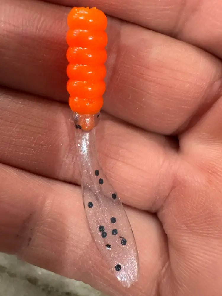 Soft plastic Crappie jig 2 inches long with a shiny orange head and a translucent clear flat beaver tail with black glitter