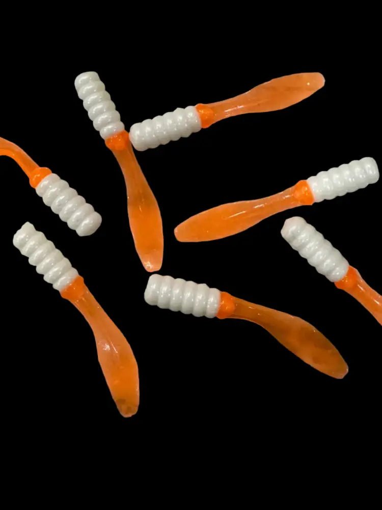 Soft plastic Crappie jigs 2 inches long with a pearl white head and translucent orange flat beaver tail